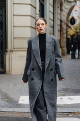 a lady wears a grey overcoat with black  knitted top